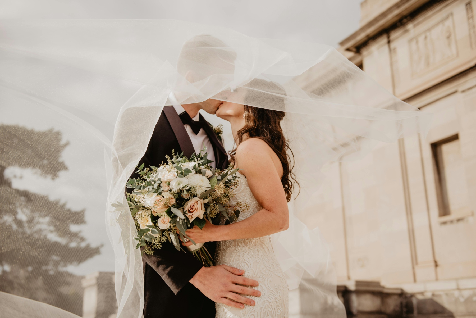 Bride and groom kissing under veil