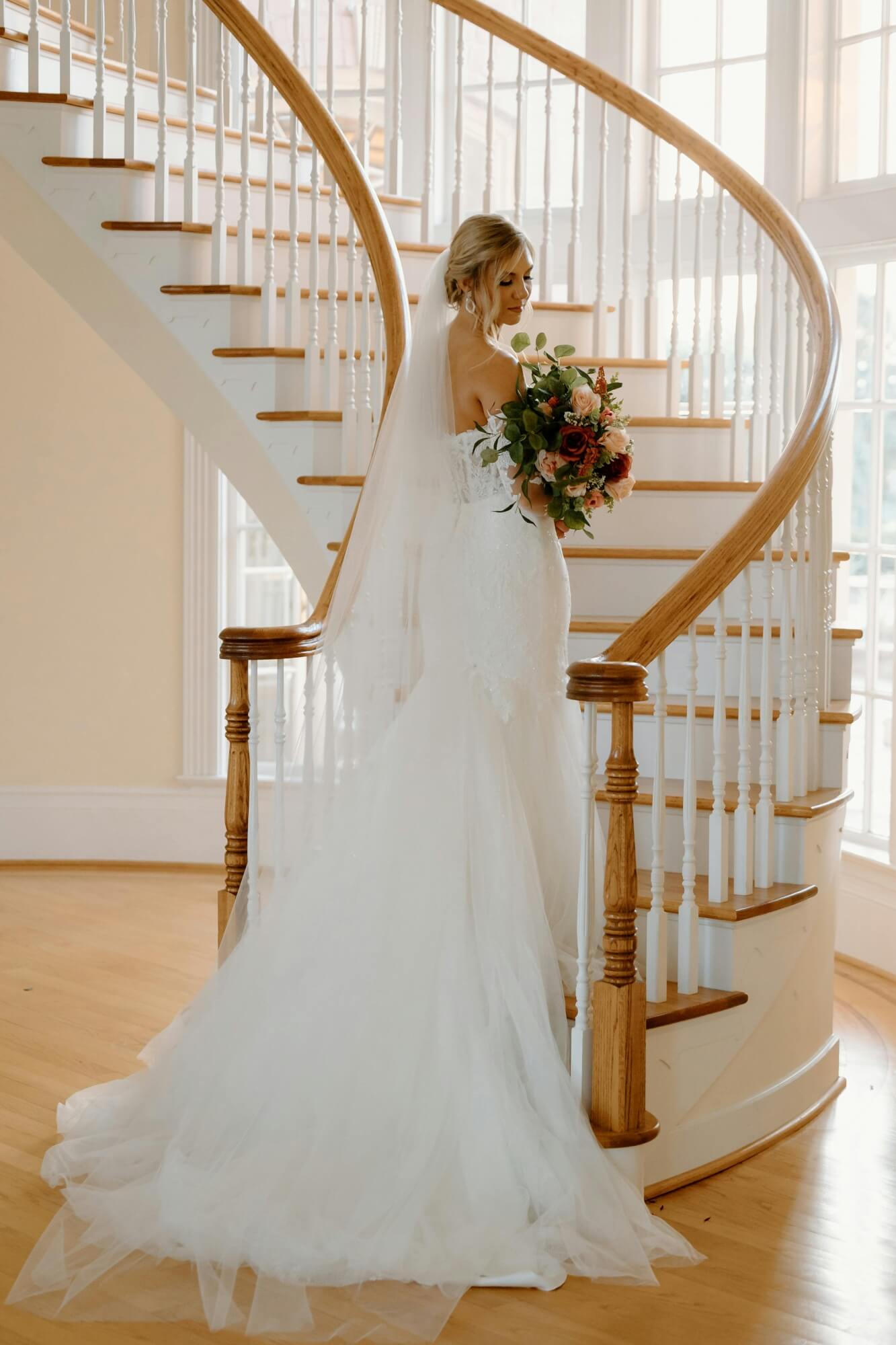 A bride walking up a spiral staircase at high-end wedding venue.